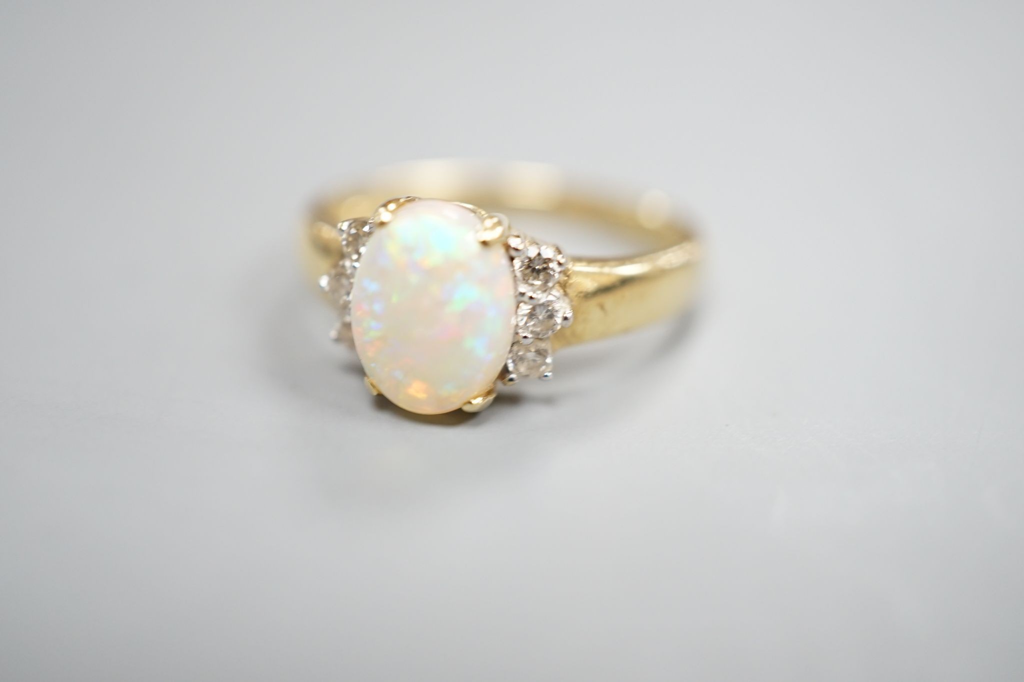 A modern 14k yellow metal, oval white opal and six stone diamond set cluster ring, size N, gross weight 2.9 grams.
